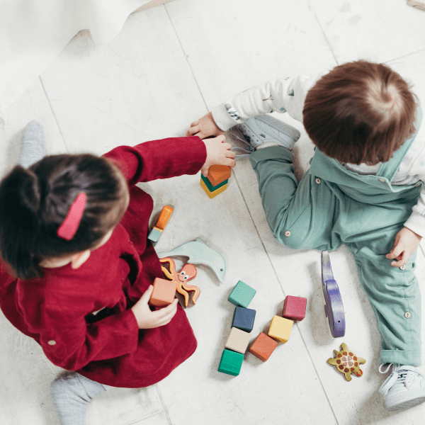 Veilige grondbox in kinderopvangruimte met peuters die spelen, duurzame materialen en zachte speelmat